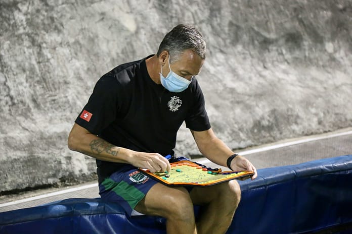 Football coach analyzing team tactics on a board, symbolizing modern formations such as the 3-5-2.