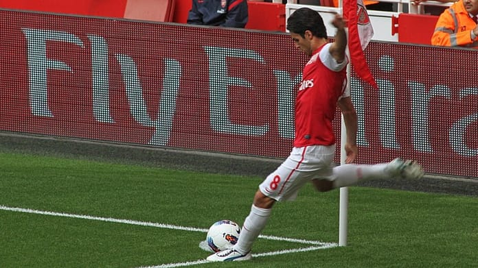 Mikel Arteta taking a corner kick for Arsenal during a Premier League match against Swansea City.