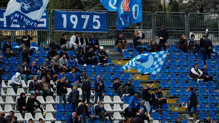 Fans waving blue flags at Stadio Giuseppe Sinigaglia in Como, illustrating the atmosphere of Italy’s lower leagues and the promotion journey to Serie A.