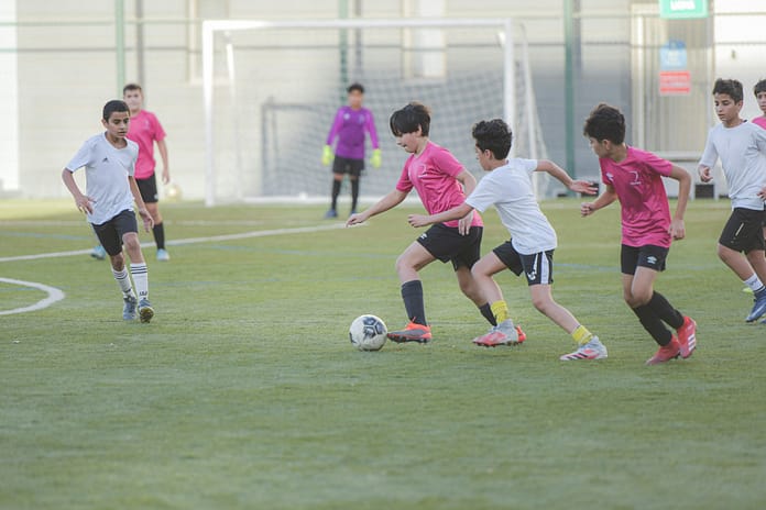 Youth training Youth football players in pink and white jerseys compete during a training match on a green pitch, with a goalkeeper in the background near the goal.