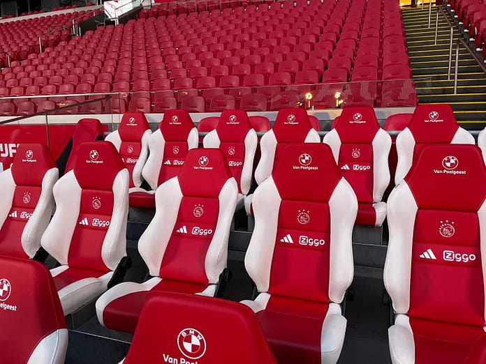 Ajax Bench 2 Red and white Ajax substitute bench seats at Johan Cruyff Arena, symbolizing the challenge and opportunity of not starting in football.