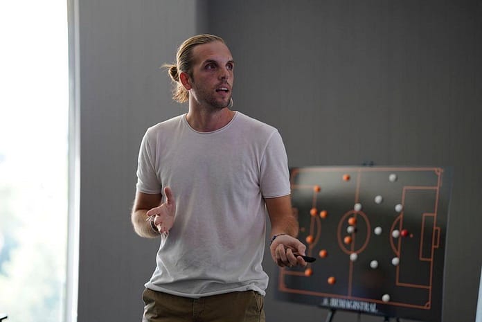 Andrés García presenting tactical insights with a football strategy board during a coaching session.